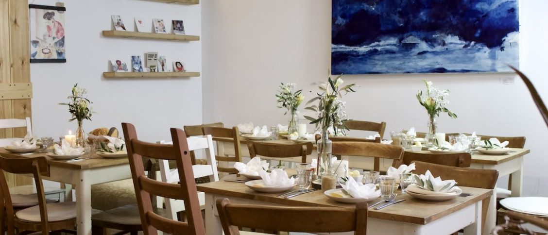 Innenansicht eines kleinen Cafés mit schön dekorierten Tischen und Wänden.